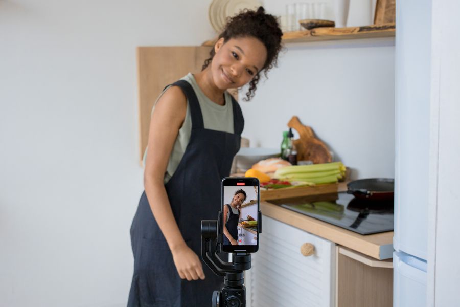 Smiling creator filming a cooking video at home