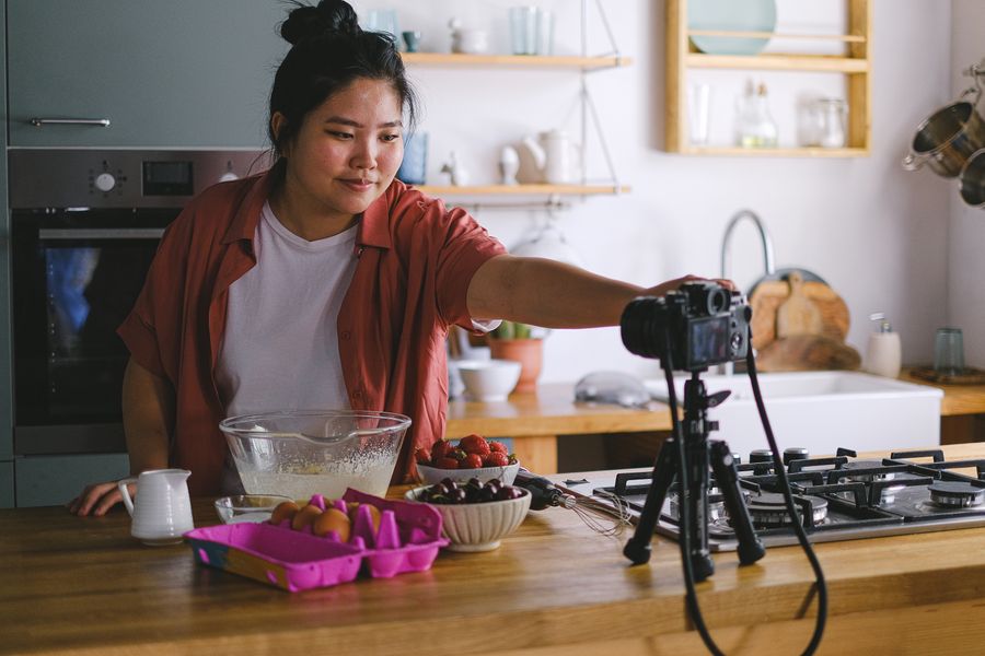 Creator filming a cooking vlog in a modern kitchen