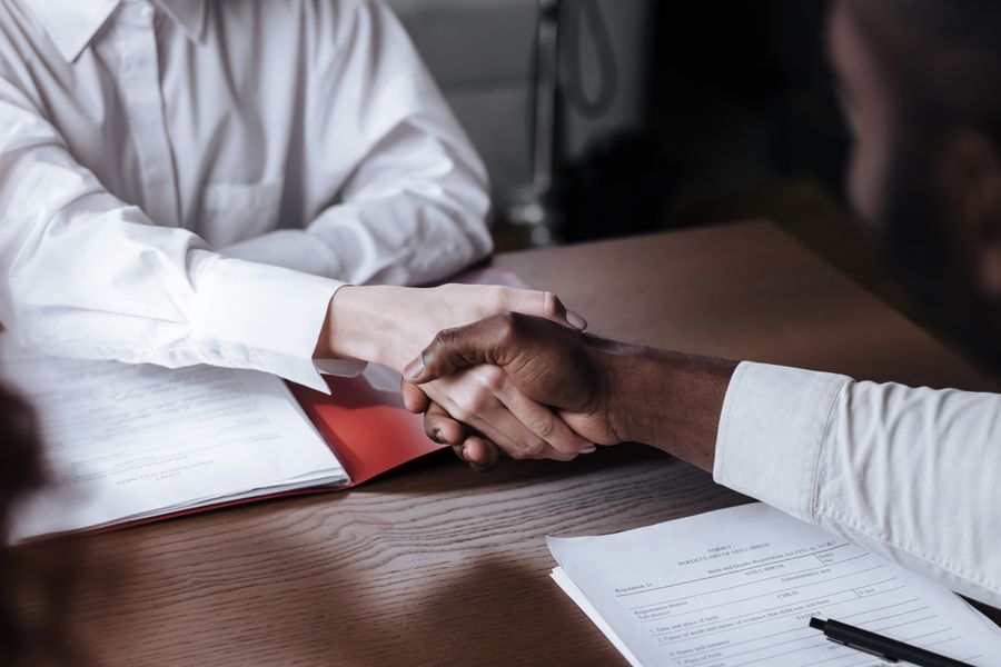 Two professionals shaking hands over deal documents